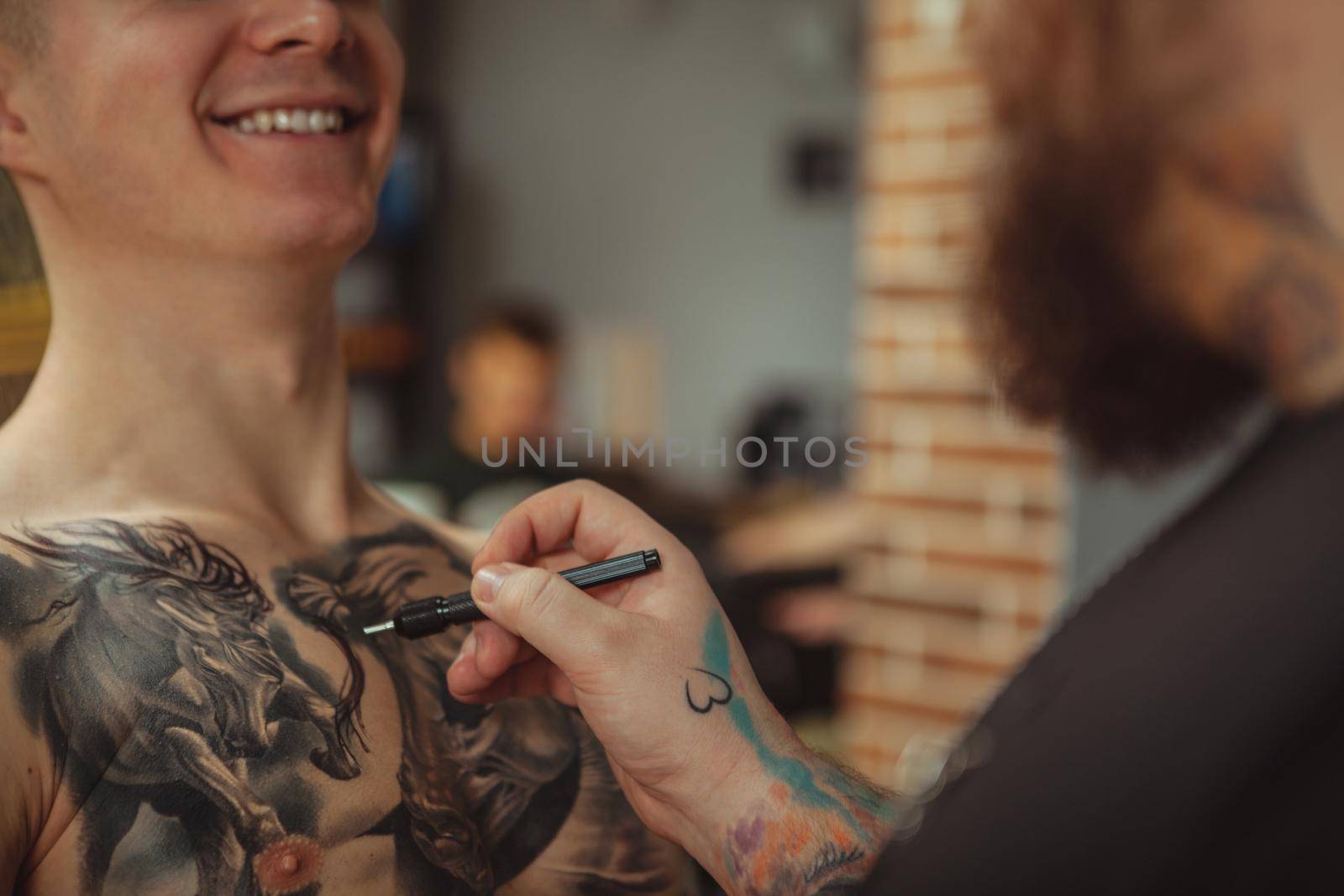 Tattoo artist working with his client at art studio by MAD_Production