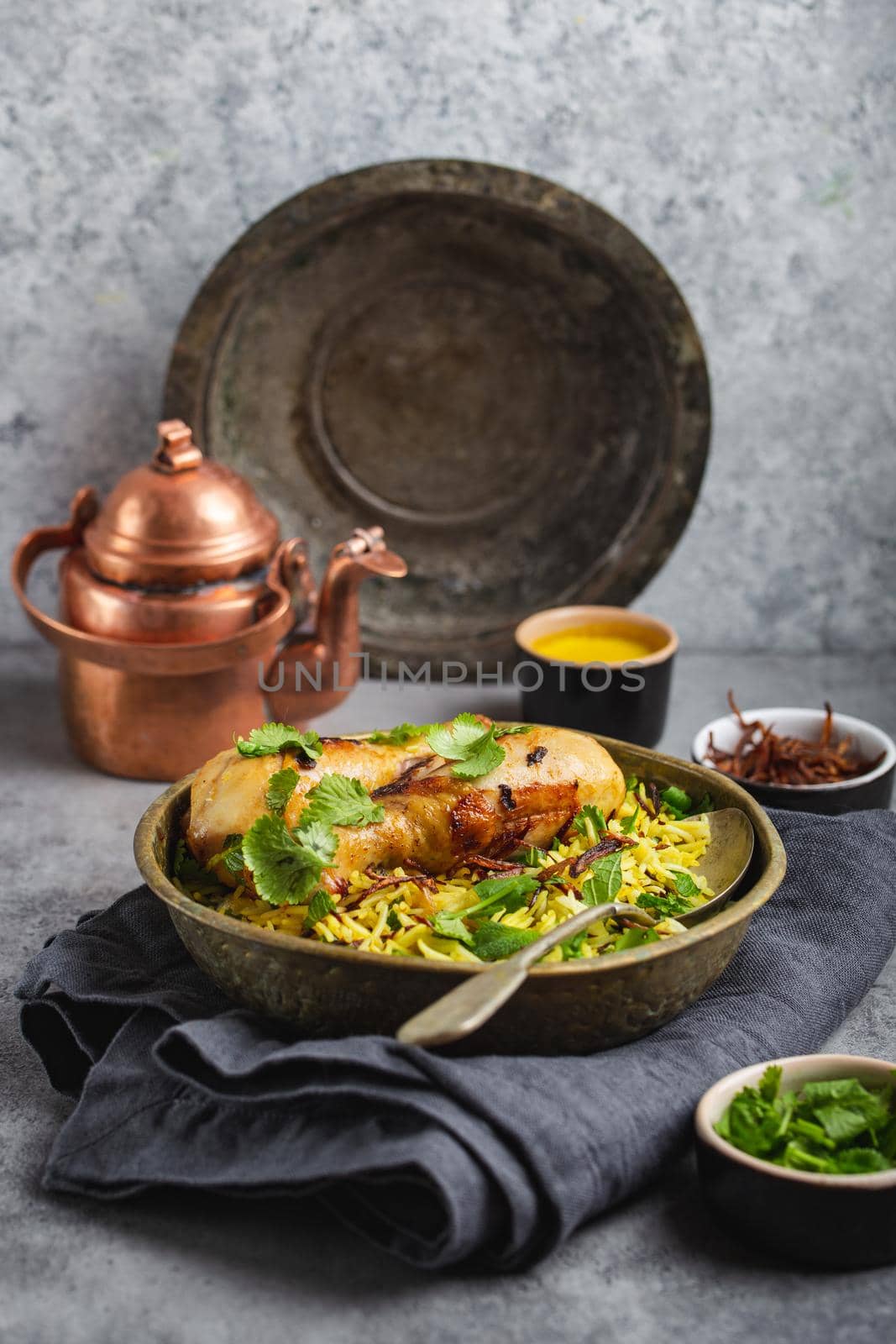 Biryani chicken, traditional dish of Indian cuisine, with basmati rice, fried onion, fresh cilantro in bowl on gray rustic stone background. Authentic Indian meal, close-up, selective focus