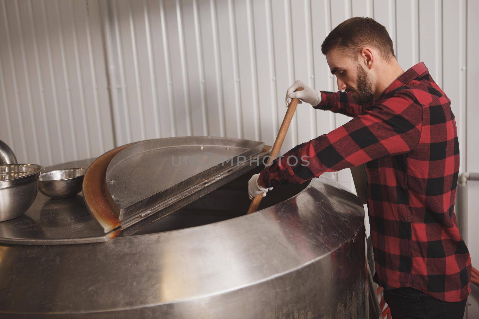 Handsome bearded brewer controlling beer fermentation process at his craft beer factory