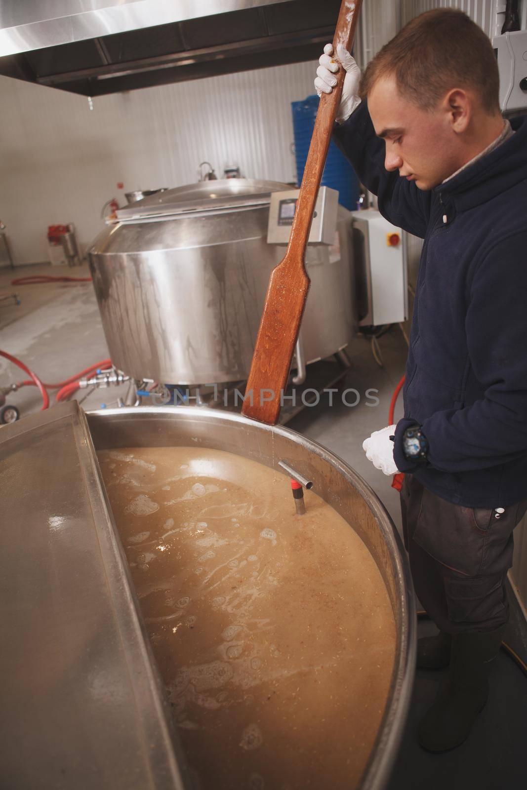 Professional brewer exmining beer in a tank during fermentation, working at craft beer factory