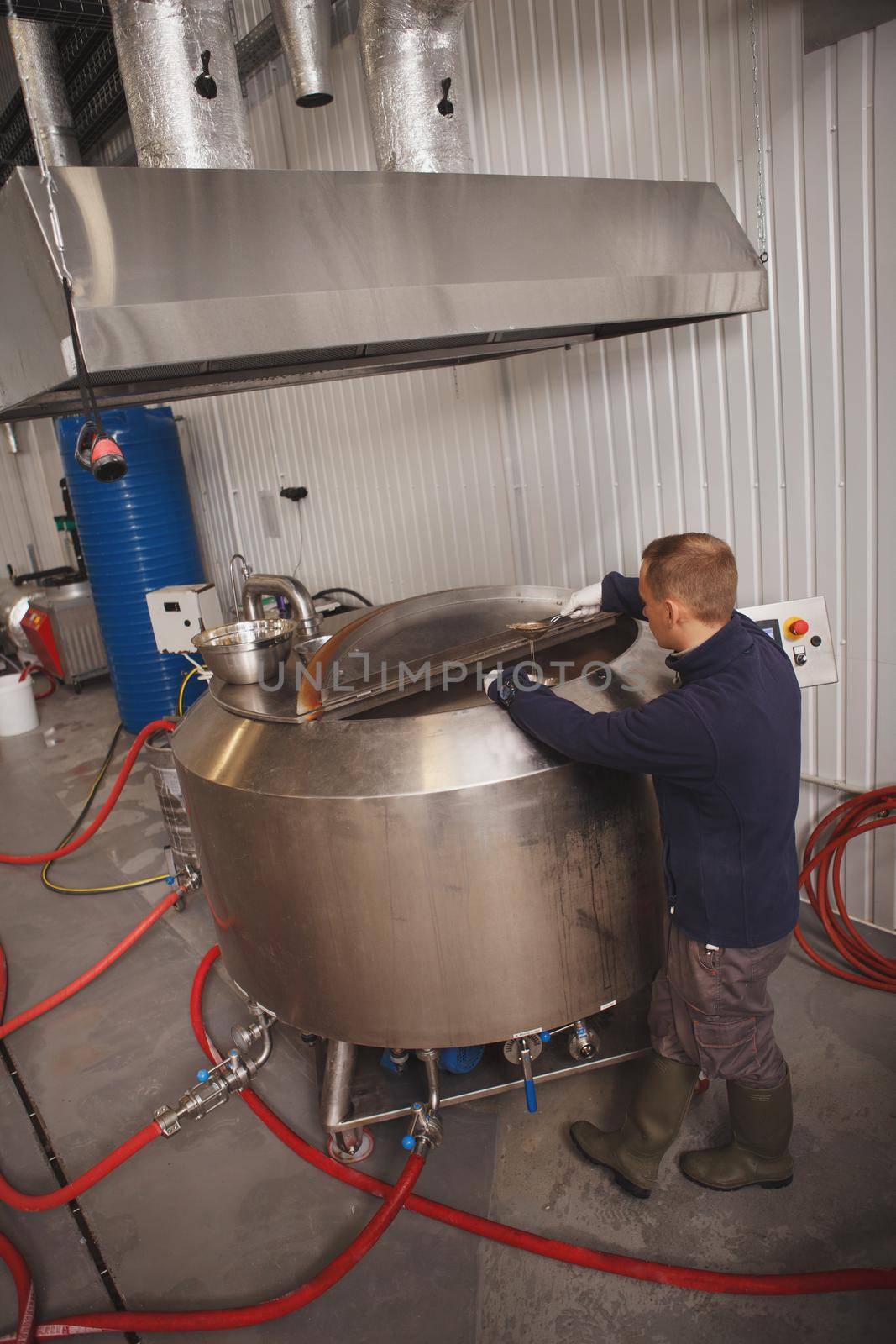 Full length rear view shot of a worker looking inside beer tank at microbrewery