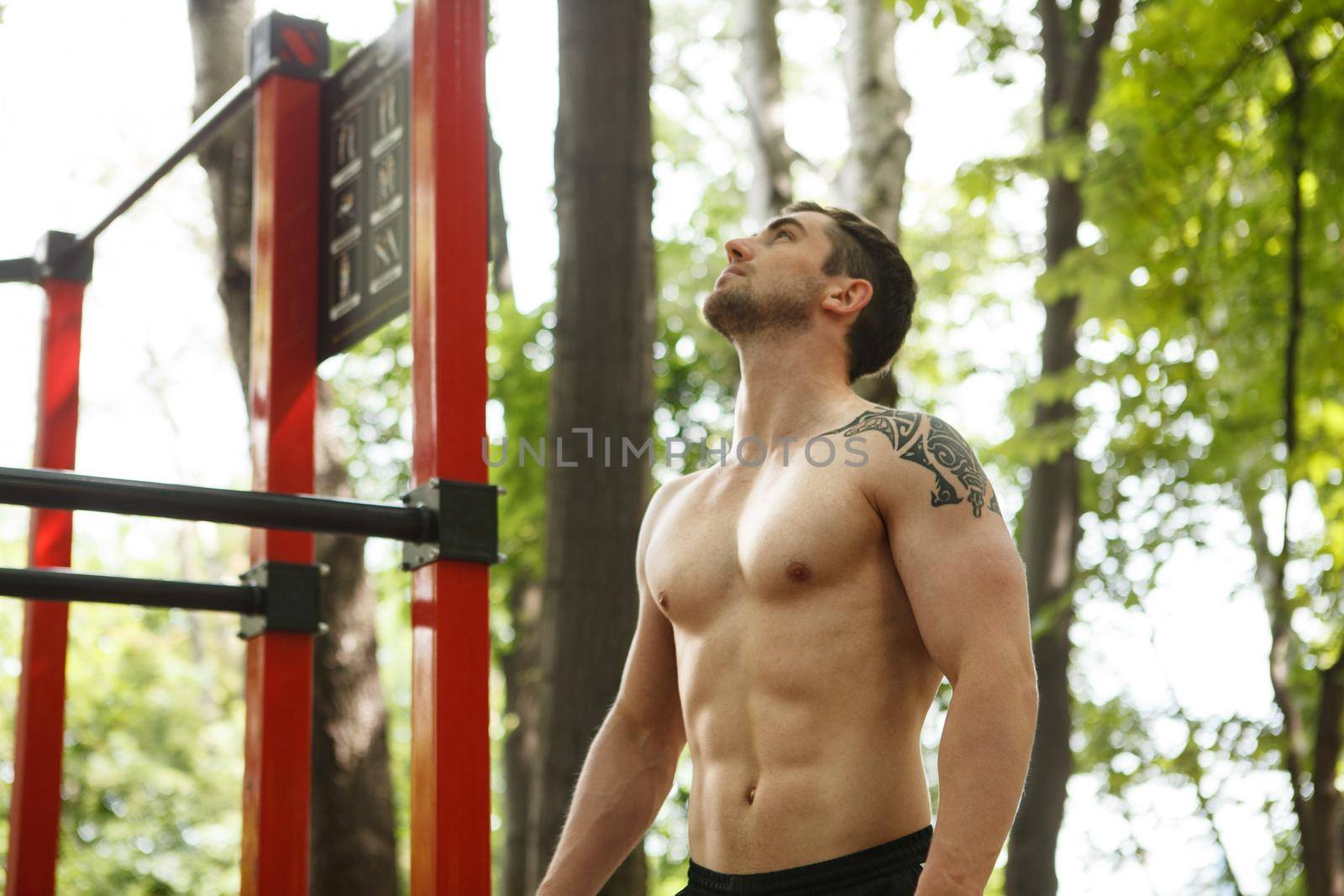 Handsome muscular man standing shirtless outdoors after working out