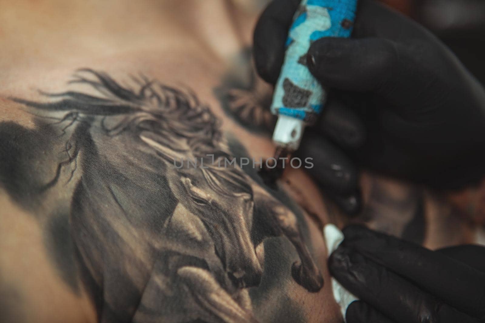 Bearded tattooist making tattoos on body of his client by MAD_Production