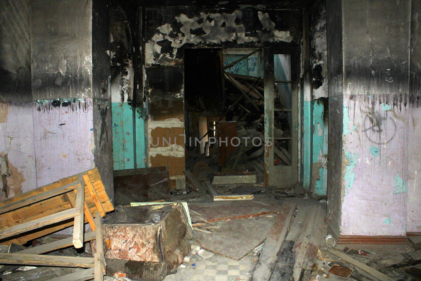 An old destroyed and charred building from the inside with the remains of things.