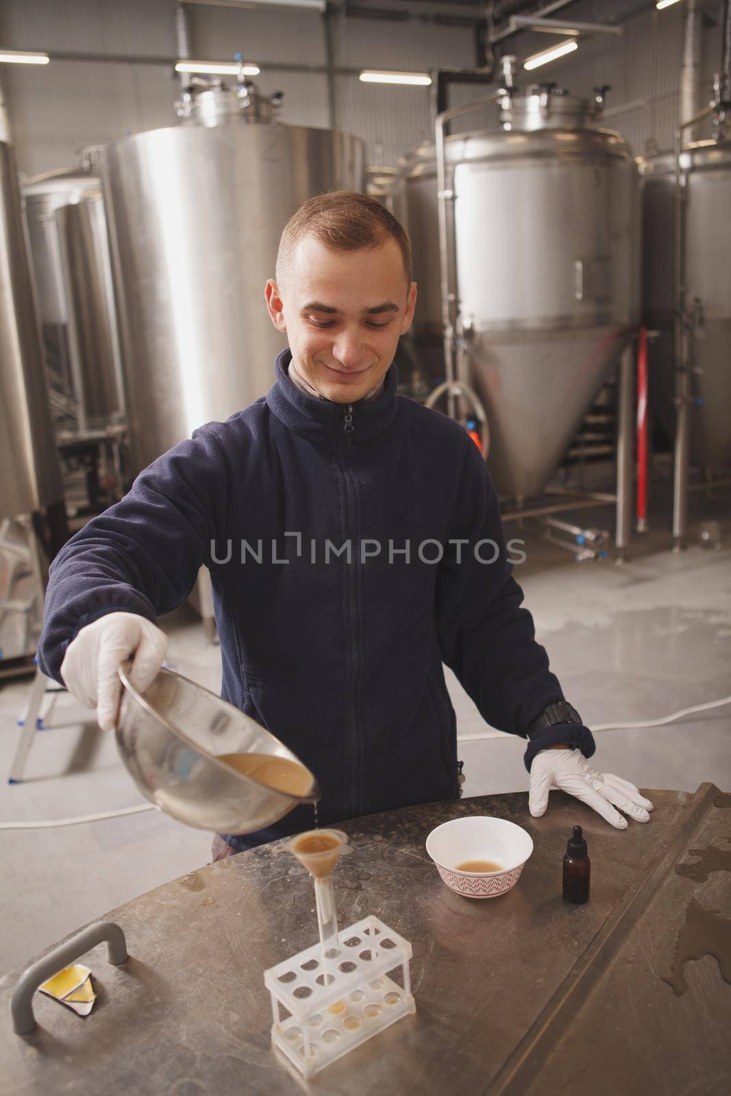 Vertical shot of a young male brewer running quality tests at microbrewery
