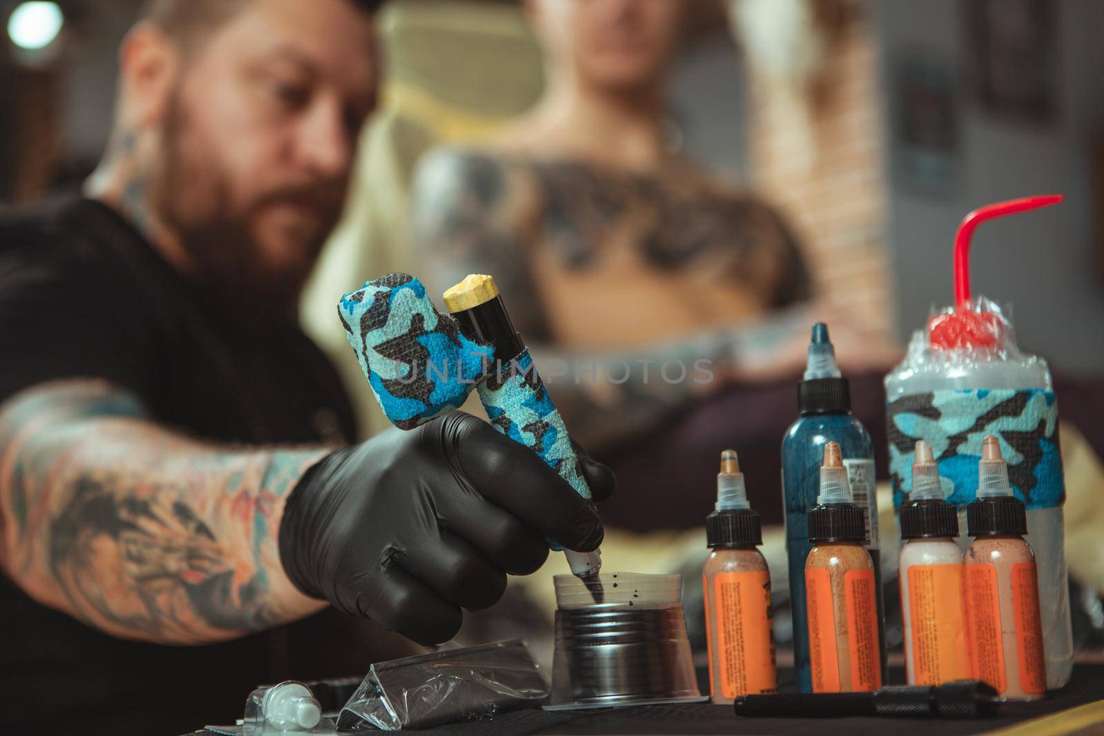Professional tattoo artist doing a new tattoo for his client by MAD_Production