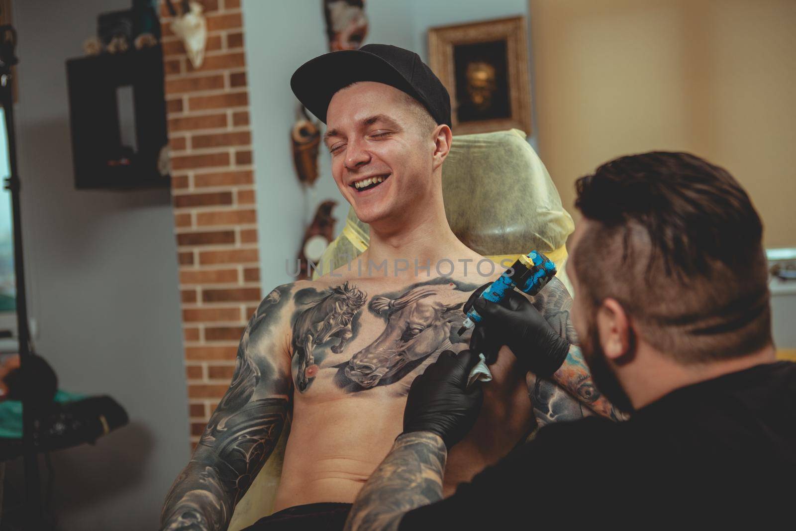 Handsome man getting a tattoo at alternative art studio by MAD_Production