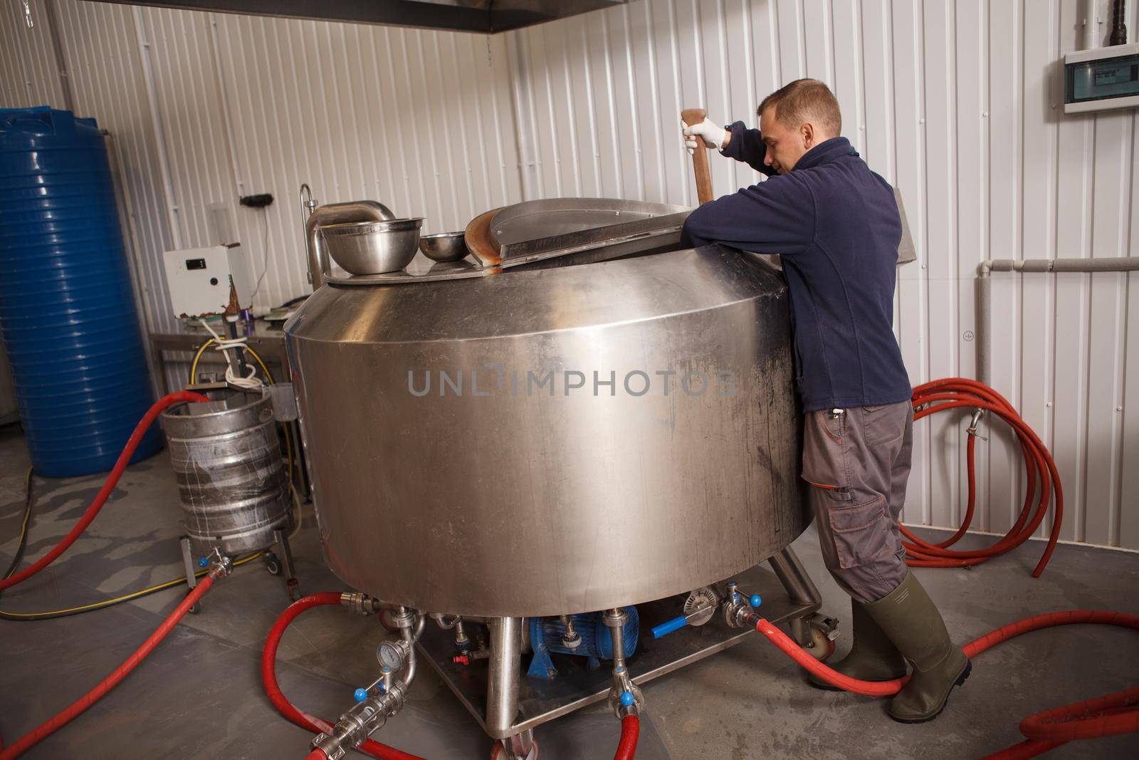 Professional brewer working at beer factory checking beer in brewing tank