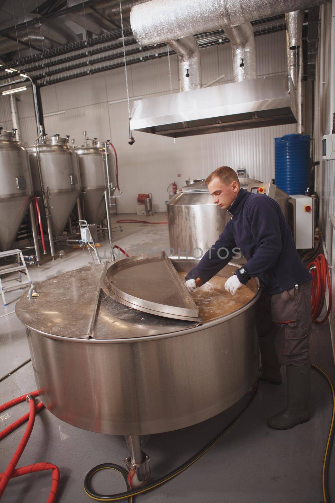 Full length vertical shot of a professional brewer looking into beer tank during fermentation process
