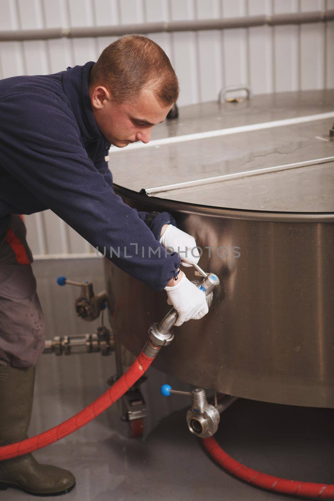 Vertical cropped shot of a maintenance worker fixing fermentation beer tank at craft beer factory