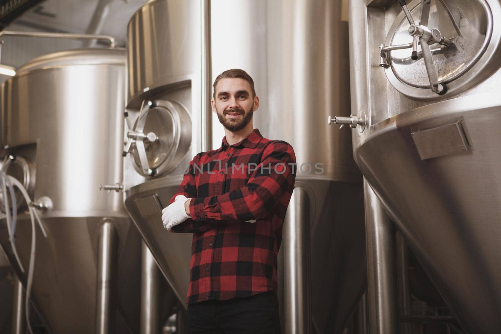 Cheerful successful brewer posing at his microbrewery