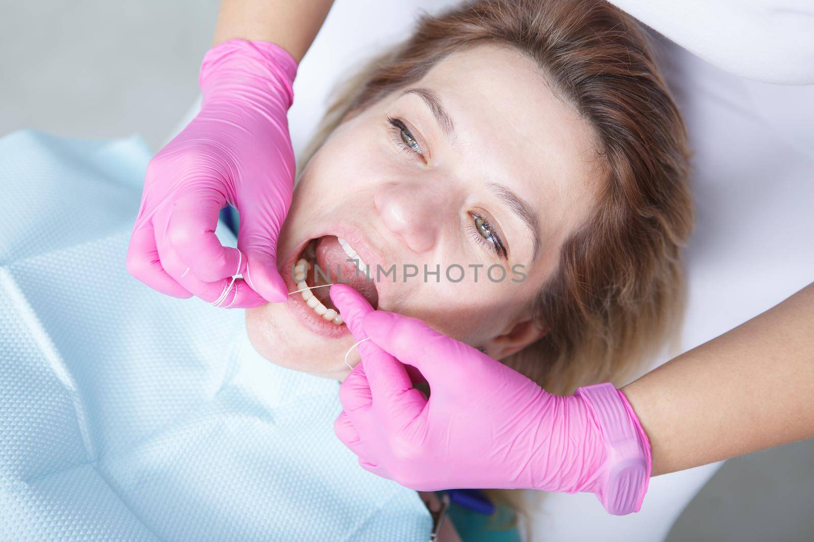 Top view close up of a mature woman having her teeth flossed by professional dentist