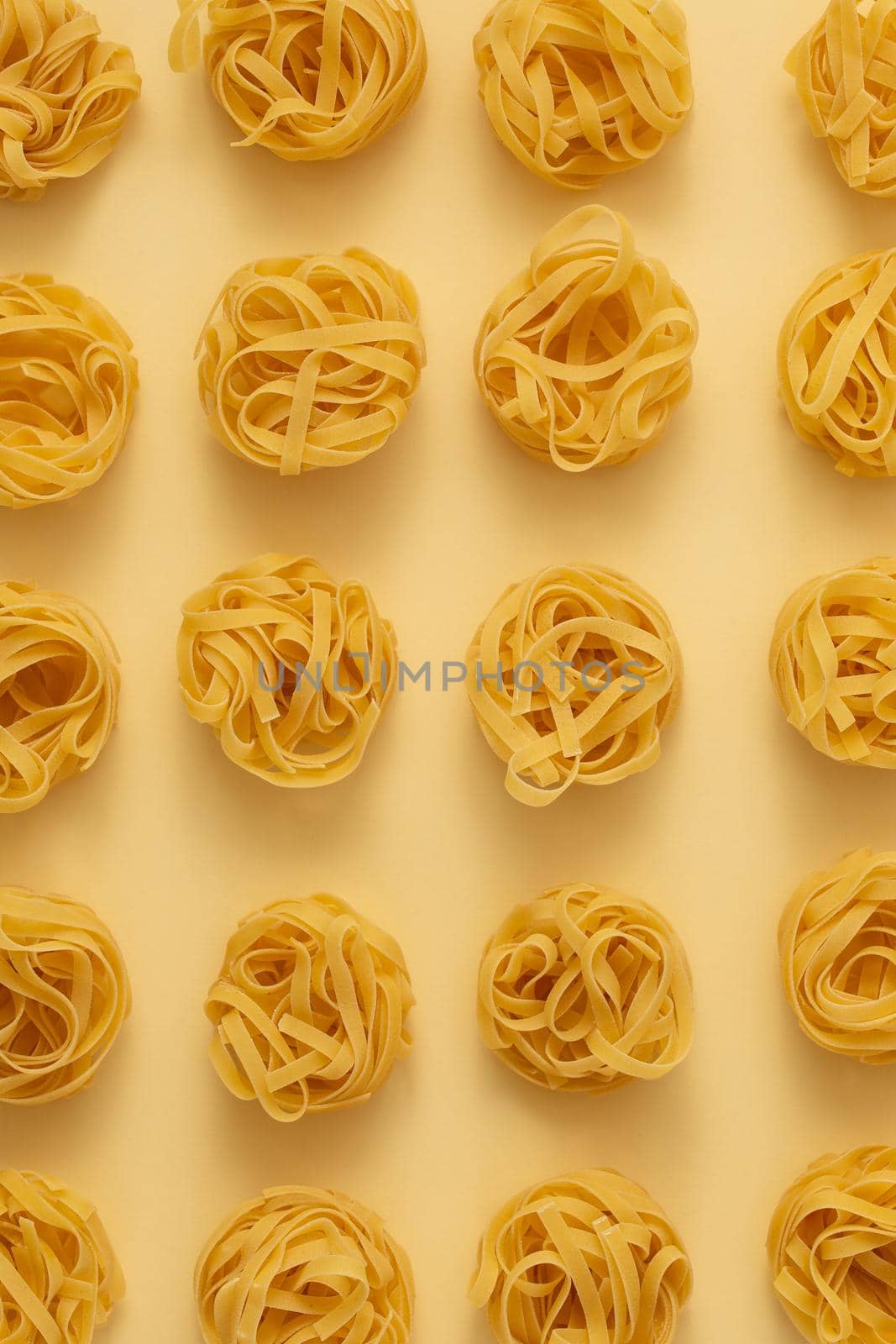 Minimal food pattern made of pasta tagliatelle on light yellow pastel background. Close up of traditional Italian pasta in pop art style. Pasta, Italian cuisine concept. Top view, flat lay