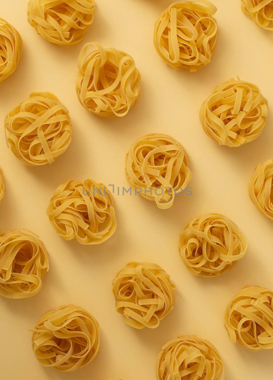 Minimal food pattern made of pasta tagliatelle on light yellow pastel background. Close up of traditional Italian pasta in pop art style. Pasta, Italian cuisine concept. Top view, flat lay