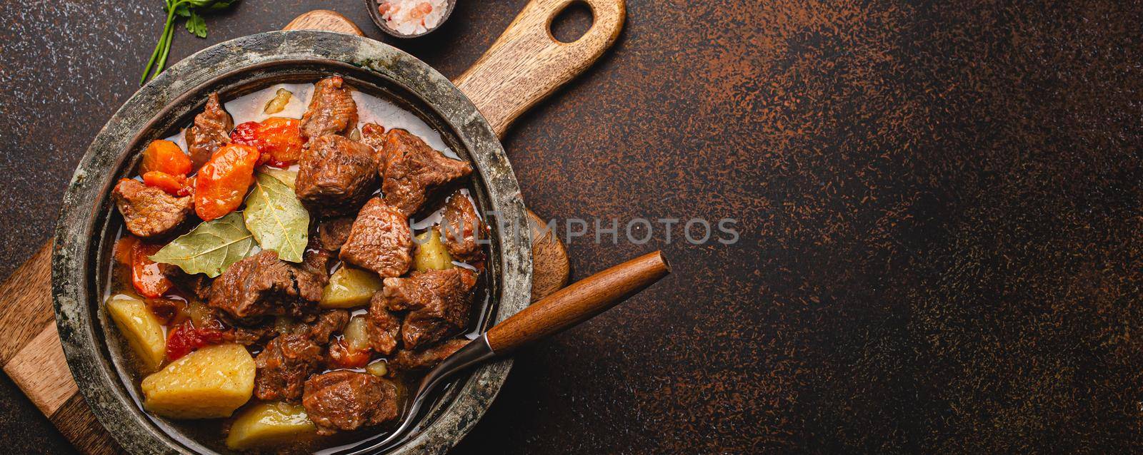 Meat beef stew with vegetables and gravy in rustic metal pot top view copy space by its_al_dente
