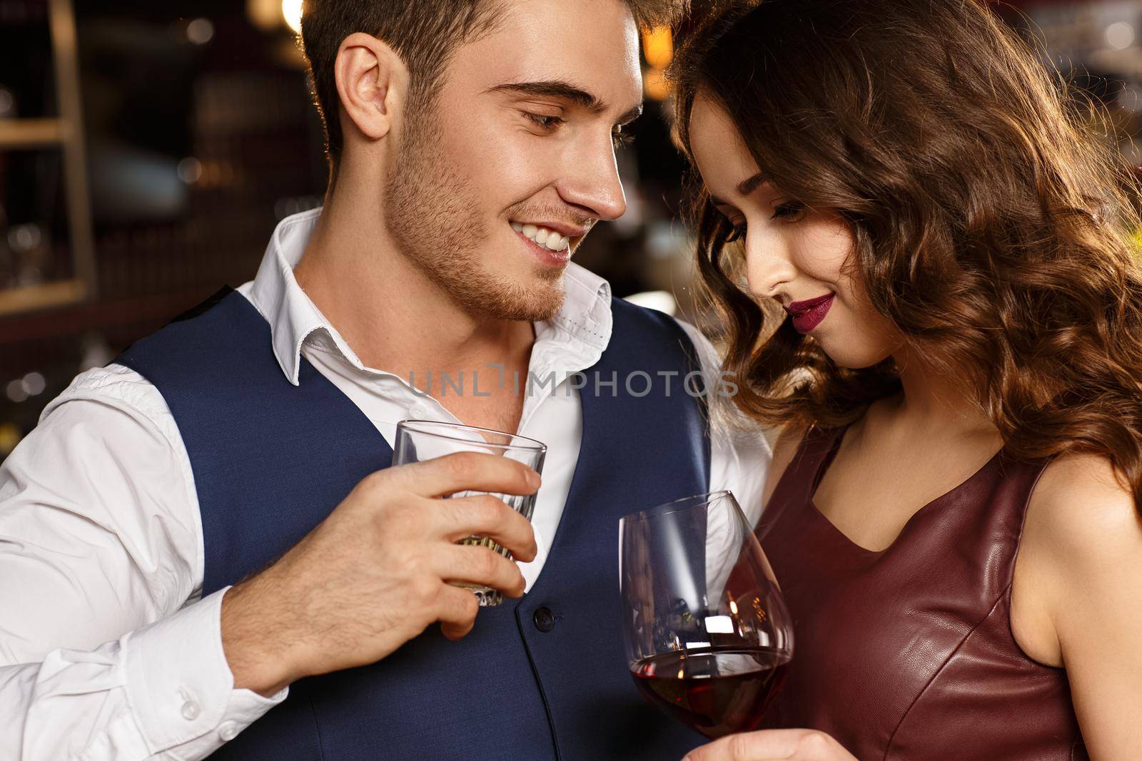 Quiet night with his lady. Shot of a handsome young man enjoying drinks with his girlfriend at the bar looking at her with love smiling warmly