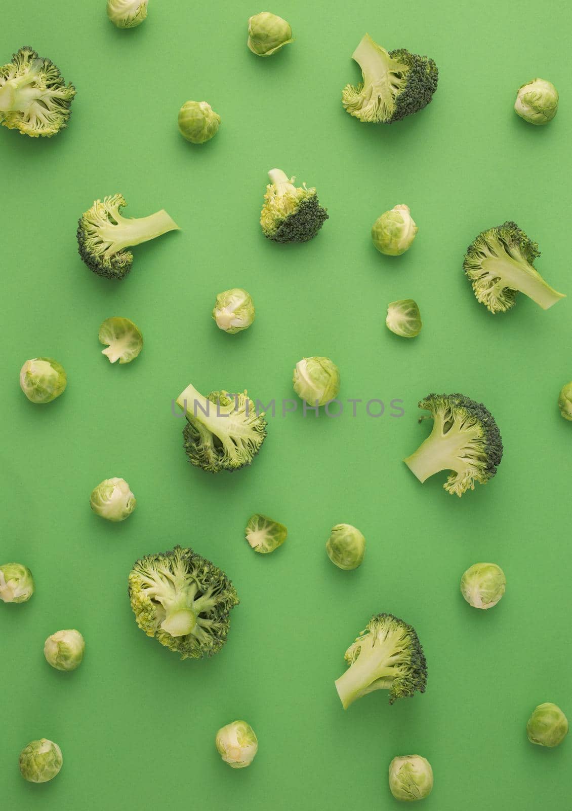 Green vegetables food pattern made of broccoli and Brussels sprouts on green background. Creative minimal flat lay design about nutrition, healthy eating, diets, vitamins. Top view