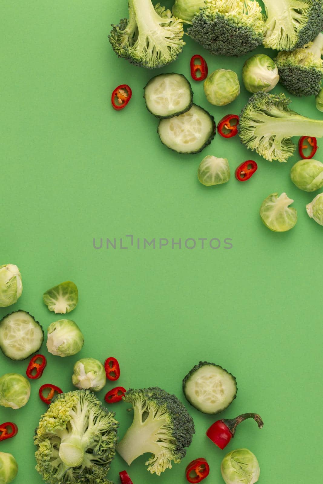 Vegetables food pattern made of broccoli, Brussels sprouts, cucumber, chili pepper, green background. Minimal flat lay design of nutrition, healthy eating, diets, vitamins. Top view, space for text