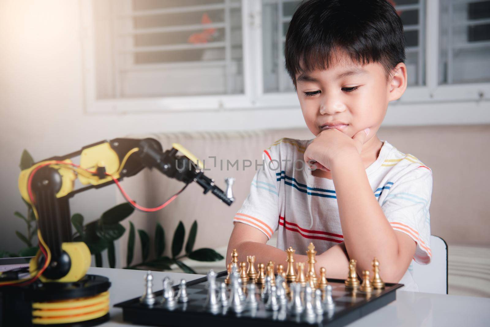 Asian little boy thinking and wait robot arm playing chess, STEM education E-learning, Funny children learning successful getting a lesson control robot arm game, Technology science education concept