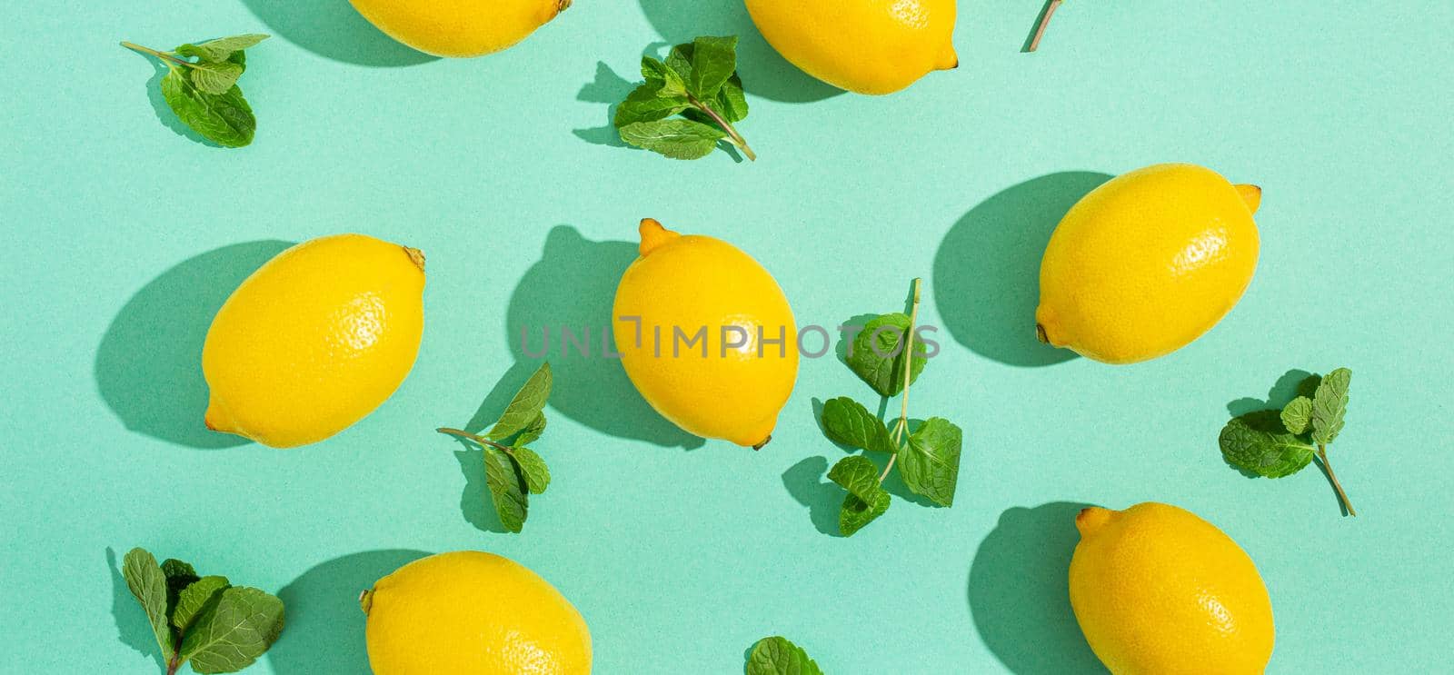 Lemons with mint on minimal blue background sun light hard shadows pattern background by its_al_dente