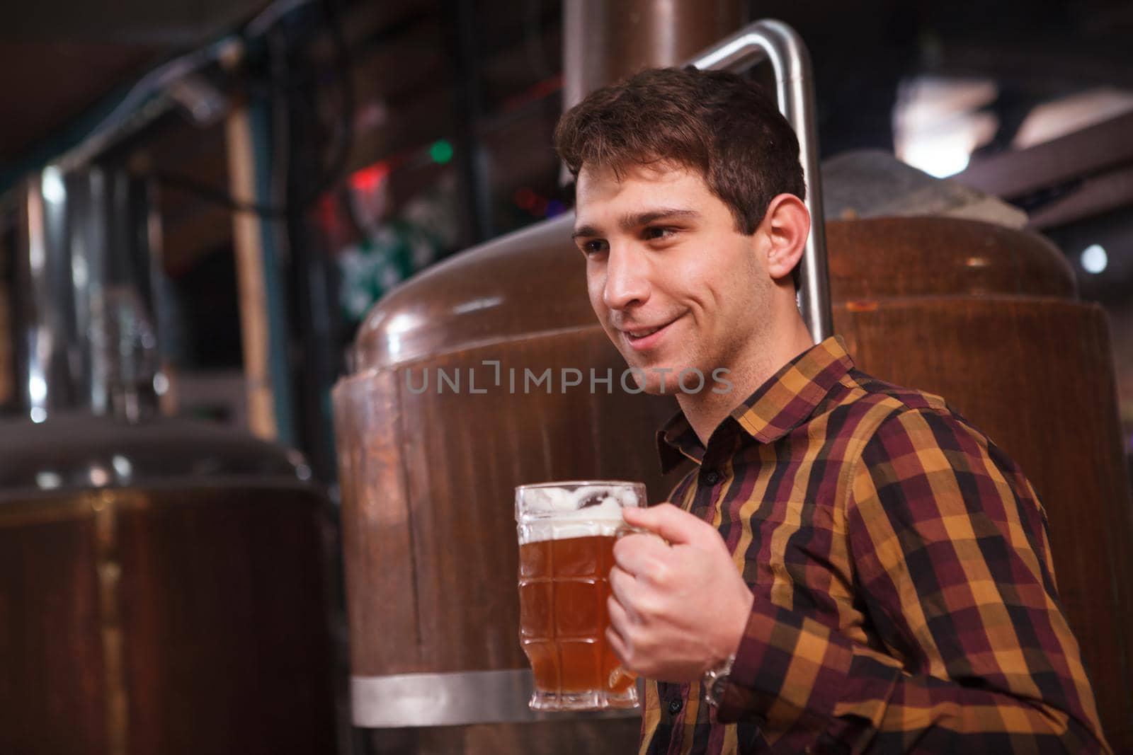 Male brewer enjoying tasting beer at his microbrewery, copy space