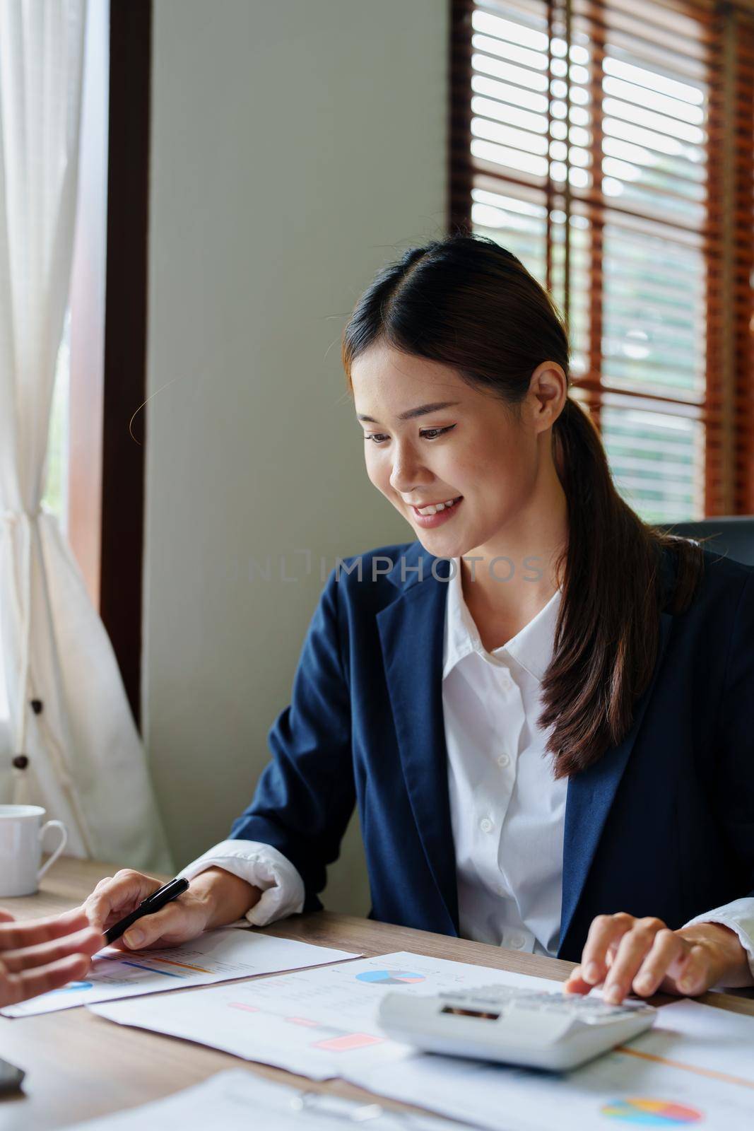 Portrait of an Asian accountant checking accounts for customers by Manastrong