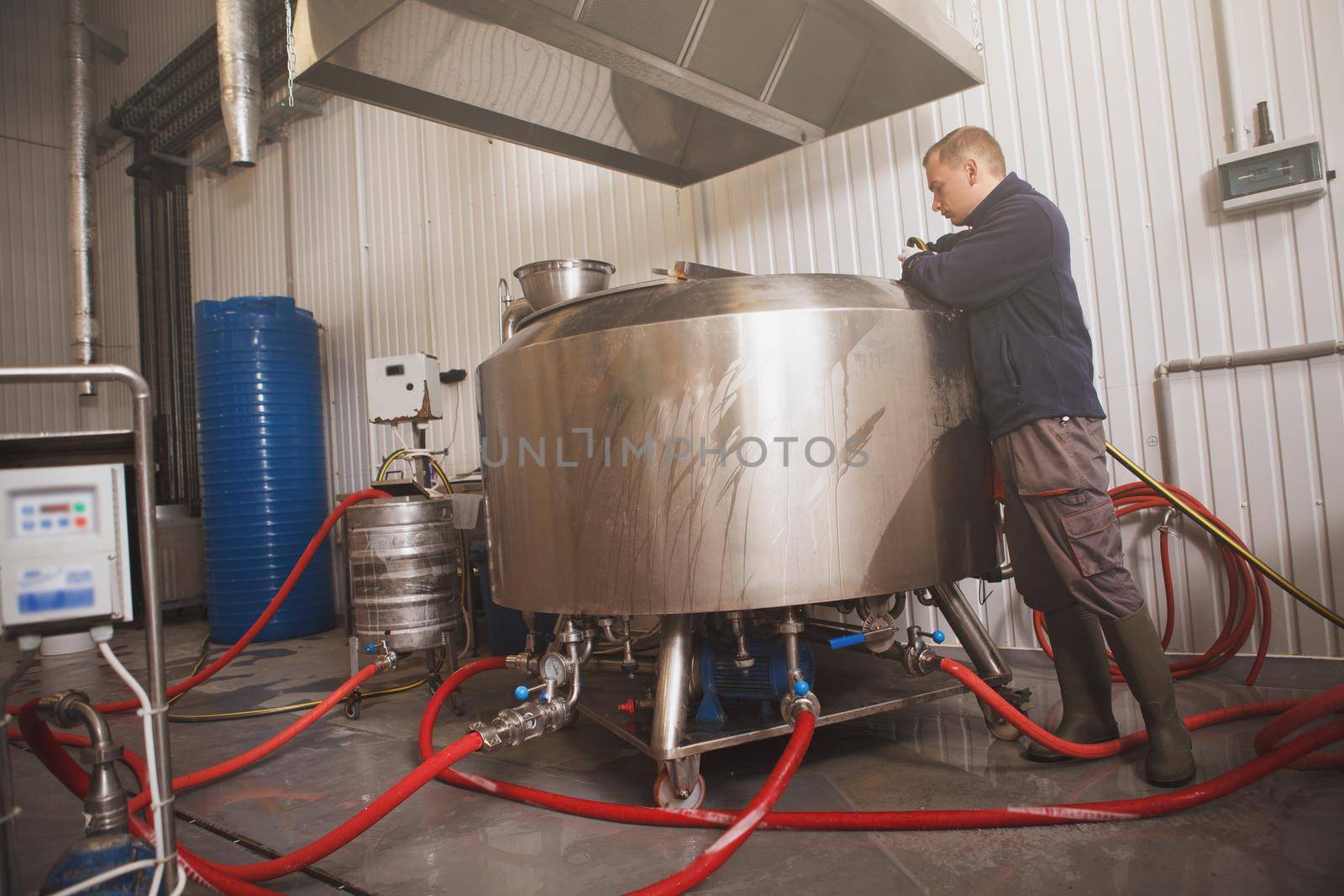 Low angle shot of a brewer looking into beer fermentation tank at craft beer factory, copy space