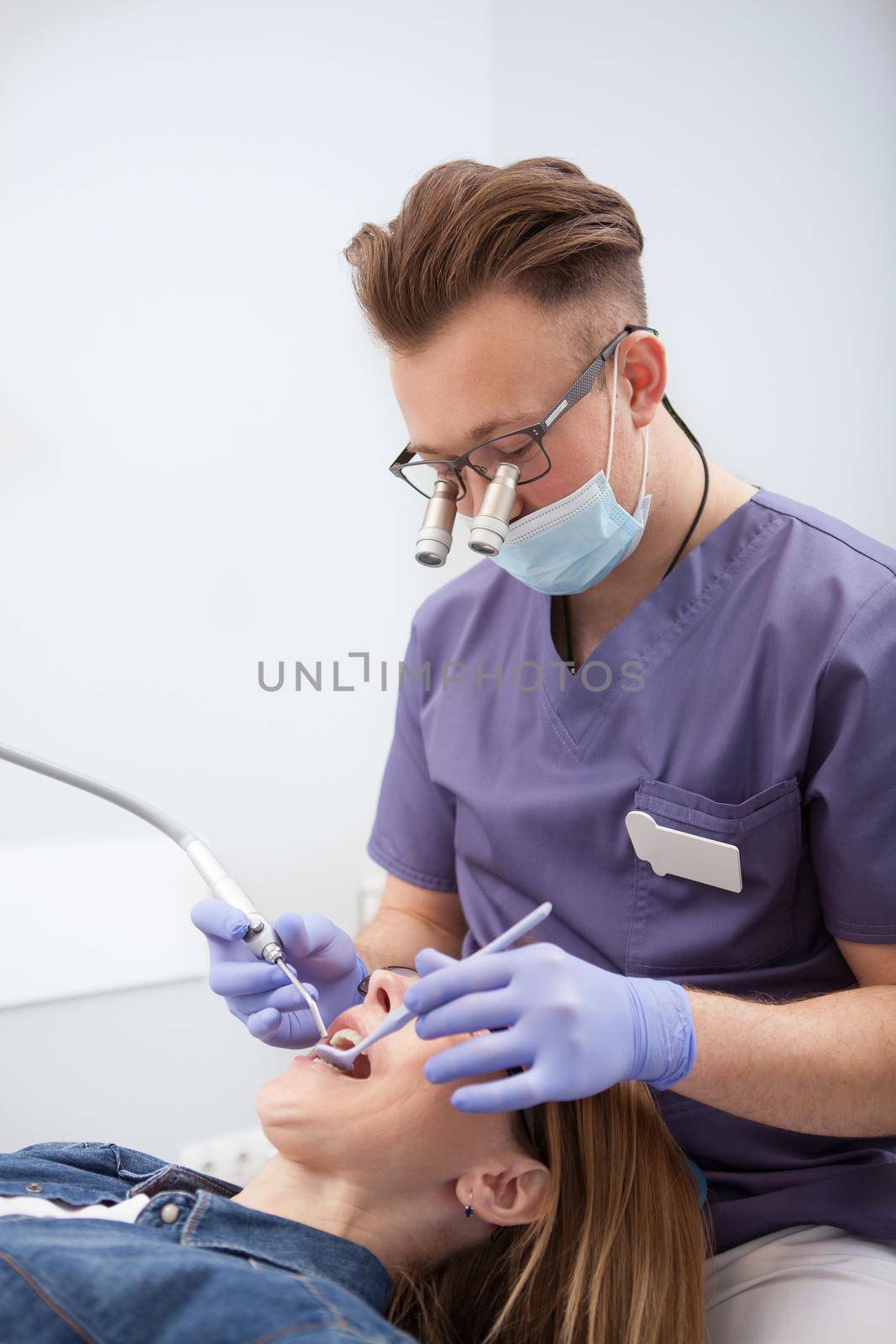 Vertical shot of a professional dentist examining teeth of female patient