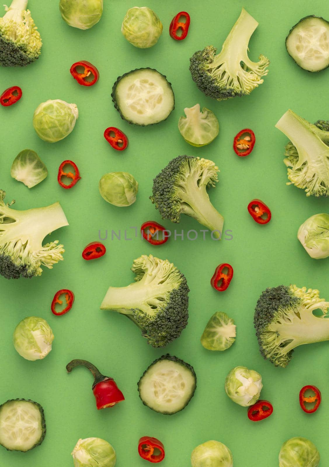Colourful vegetables food pattern made of broccoli, Brussels sprouts, cucumber, chili pepper, green background. Minimal flat lay design about nutrition, healthy eating, diets, vitamins. Top view
