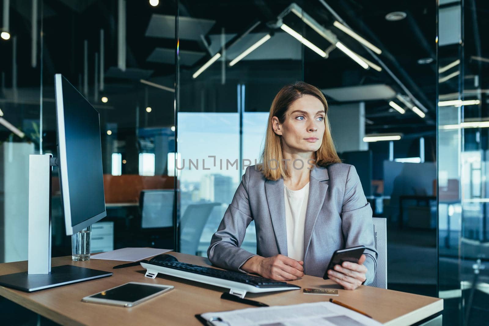 Successful woman working in a modern office on a computer, businesswoman uses the phone, social networks, online browsing