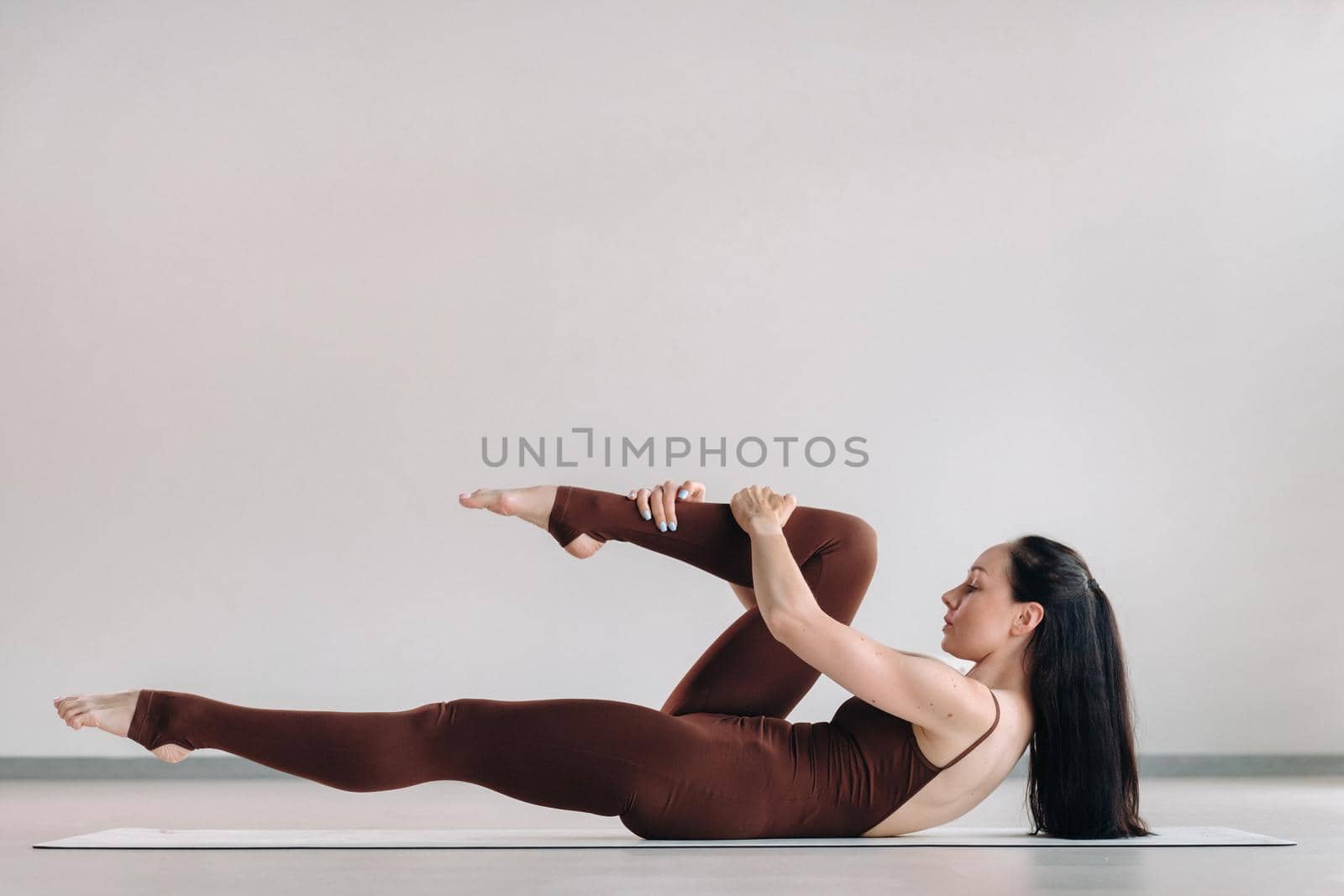 a woman in a brown suit does yoga in a fitness room . Healthy lifestyle, fitness, training, self-care by Lobachad