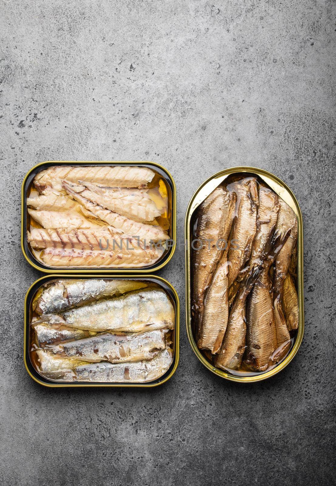 Assorted canned fish in a tin over gray concrete background: sardine, smoked sardine, mackerel. Tinned fish as a convenient, fast, healthy food and source of omega-3 fatty acids, protein and vitamin D