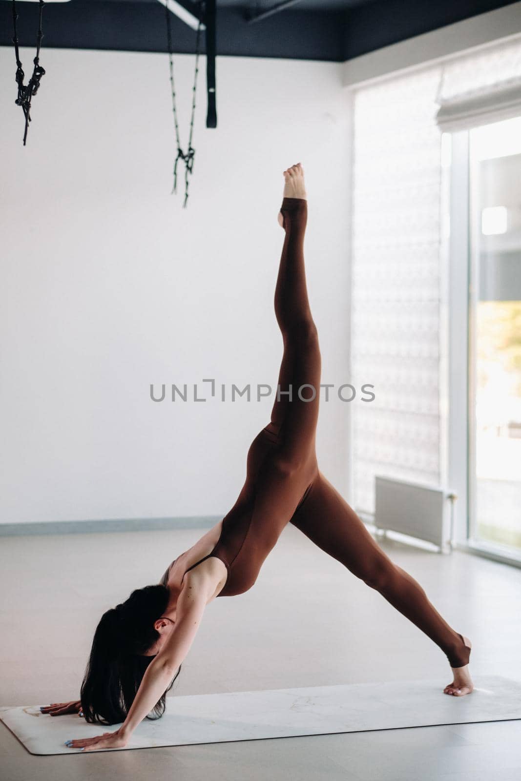 a woman in a brown suit does yoga in a fitness room . Healthy lifestyle, fitness, training, self-care.