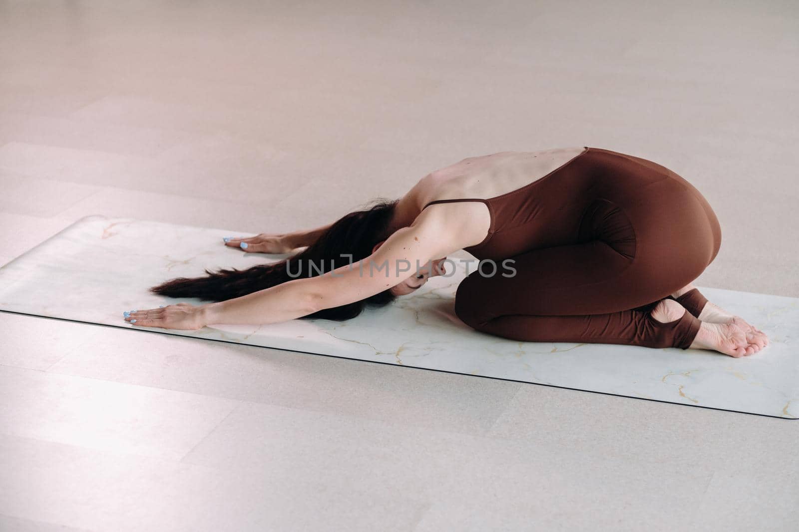 a woman in a brown suit does yoga in a fitness room . Healthy lifestyle, fitness, training, self-care.