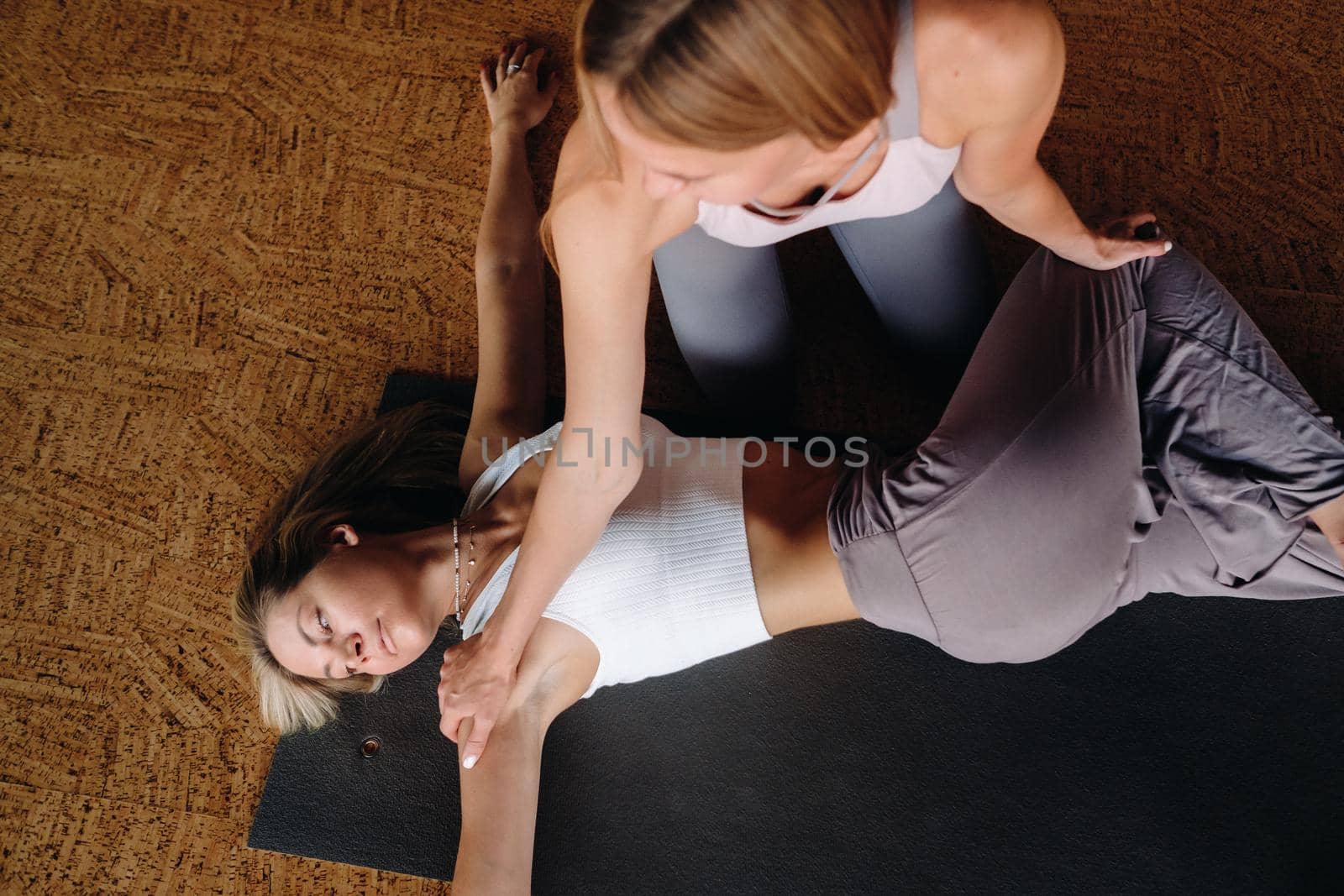 Yoga exercises. A personal trainer teaches a woman yoga classes in the gym by Lobachad