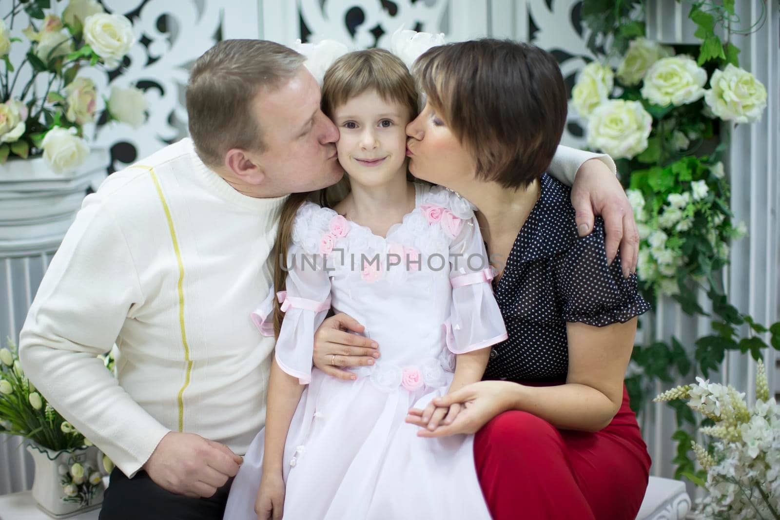 Mother and father kiss the daughter. A real family by Sviatlana