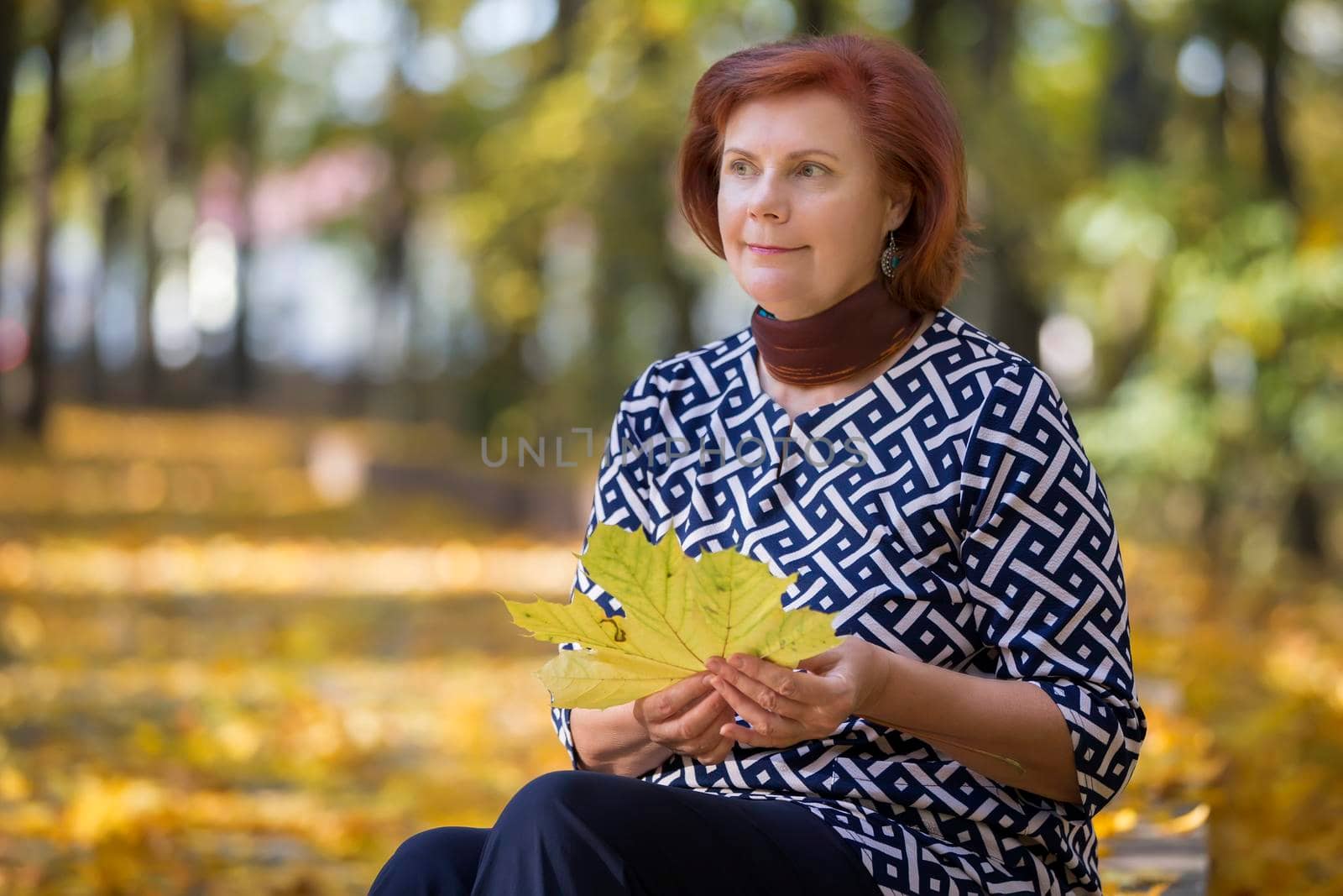 Elderly woman with autumn leaves.Autumn age