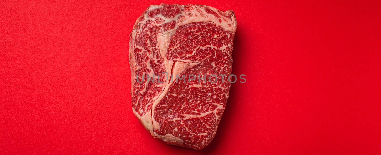 Raw meat beef prime cut steak Ribeye on clean red background from above, beefsteak concept banner minimalism by its_al_dente