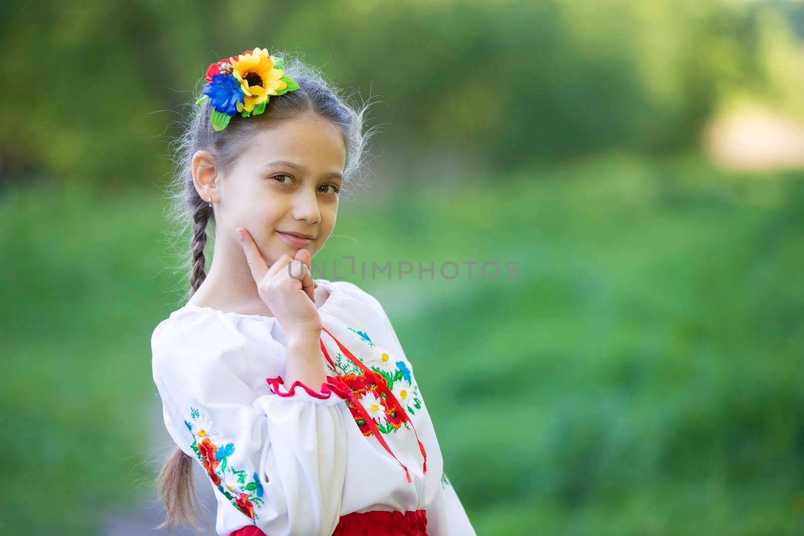 A little Ukrainian and Belarusian girl in an embroidered shirt on a summer background.