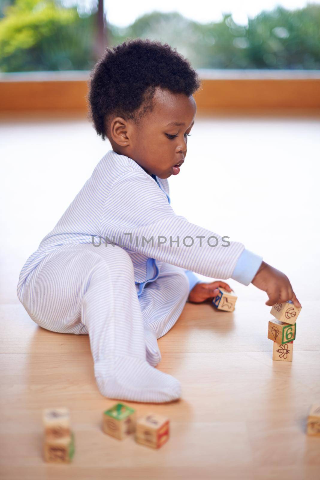 Make it fun and the learning will come. a cute baby boy playing with wooden building blocks on the floor