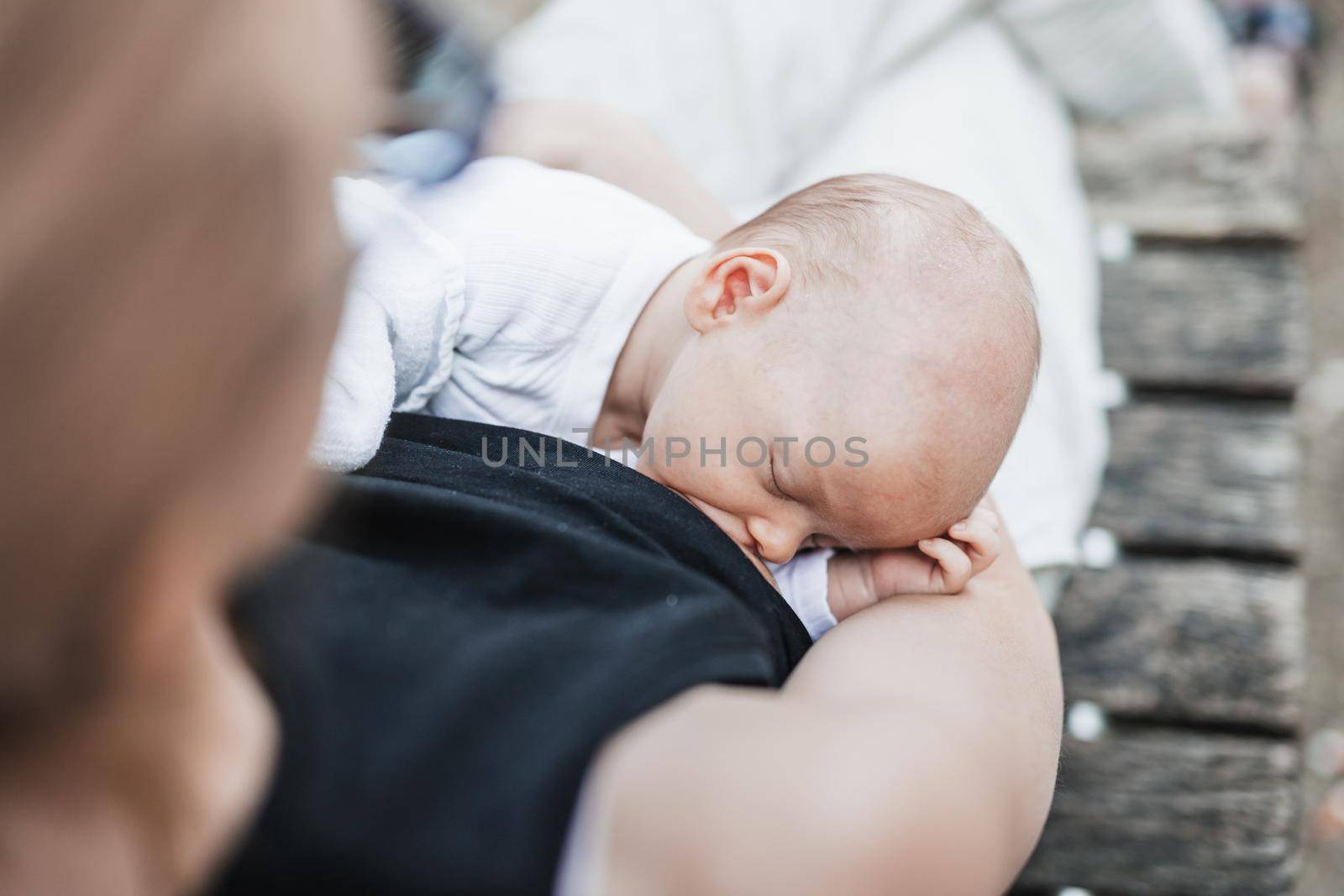 Mother breast feeding and hugging her baby boy outdoors