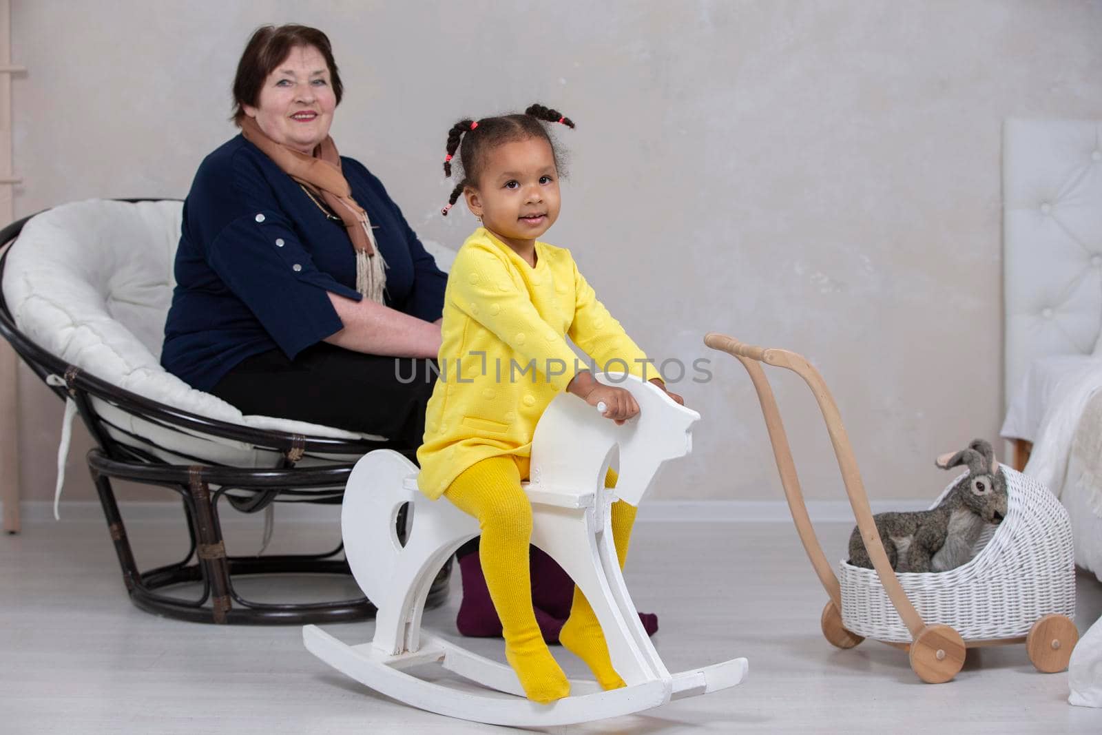 Grandmother and granddaughter from different races. The fair-skinned grandmother plays with the dark-skinned granddaughter.