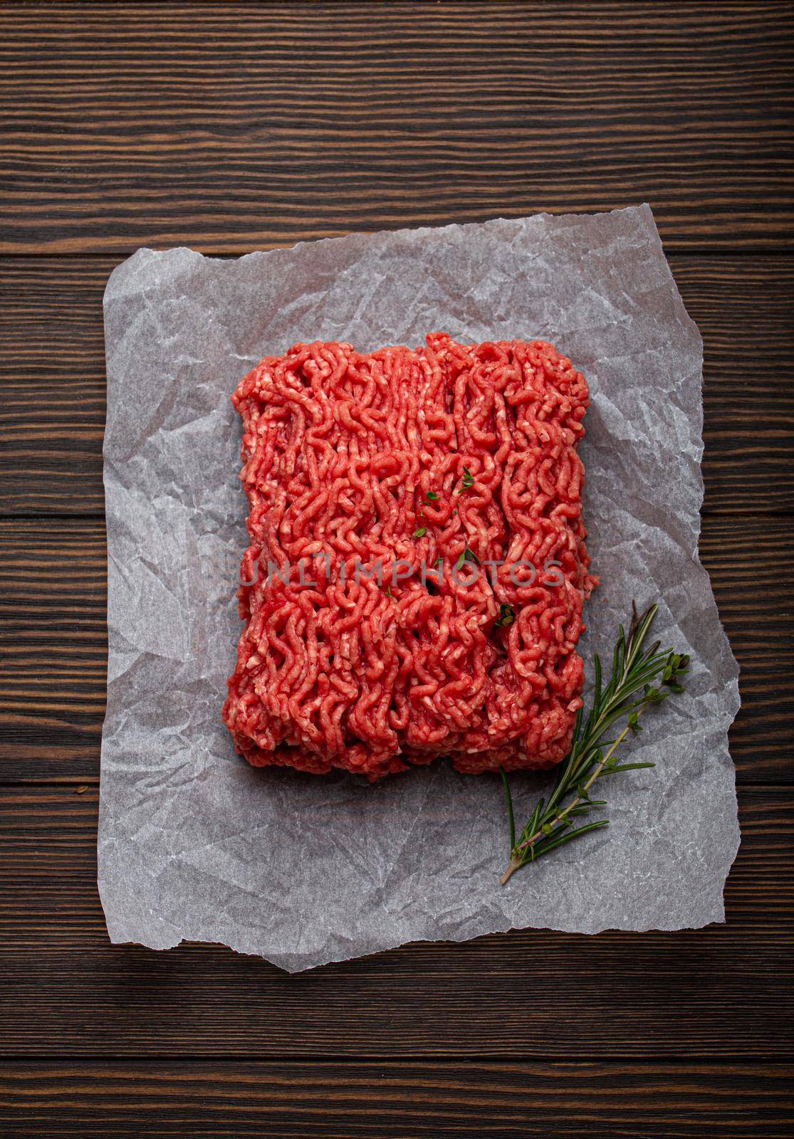 Fresh raw minced meat from ground beef or pork on cutting board and dark brown rustic wooden background from above for catalog or shop
