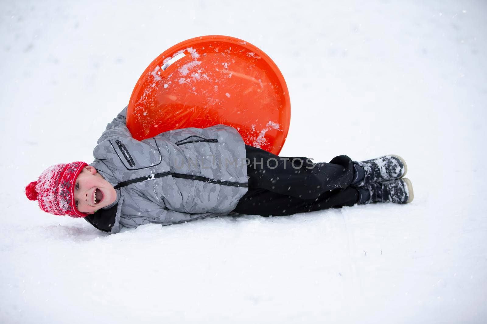 Cute young boy smiling while he is sledding