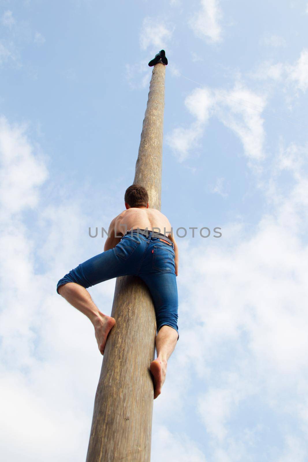 Celebration of carnival. The man climbs on the pillar. Maslenitsa