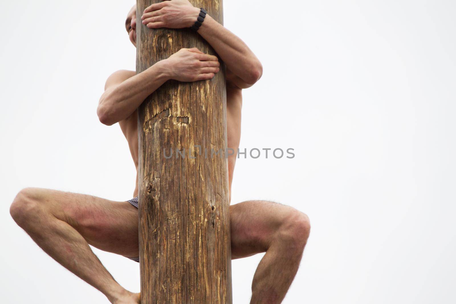 Celebration of carnival. The man climbs on the pillar. Maslenitsa