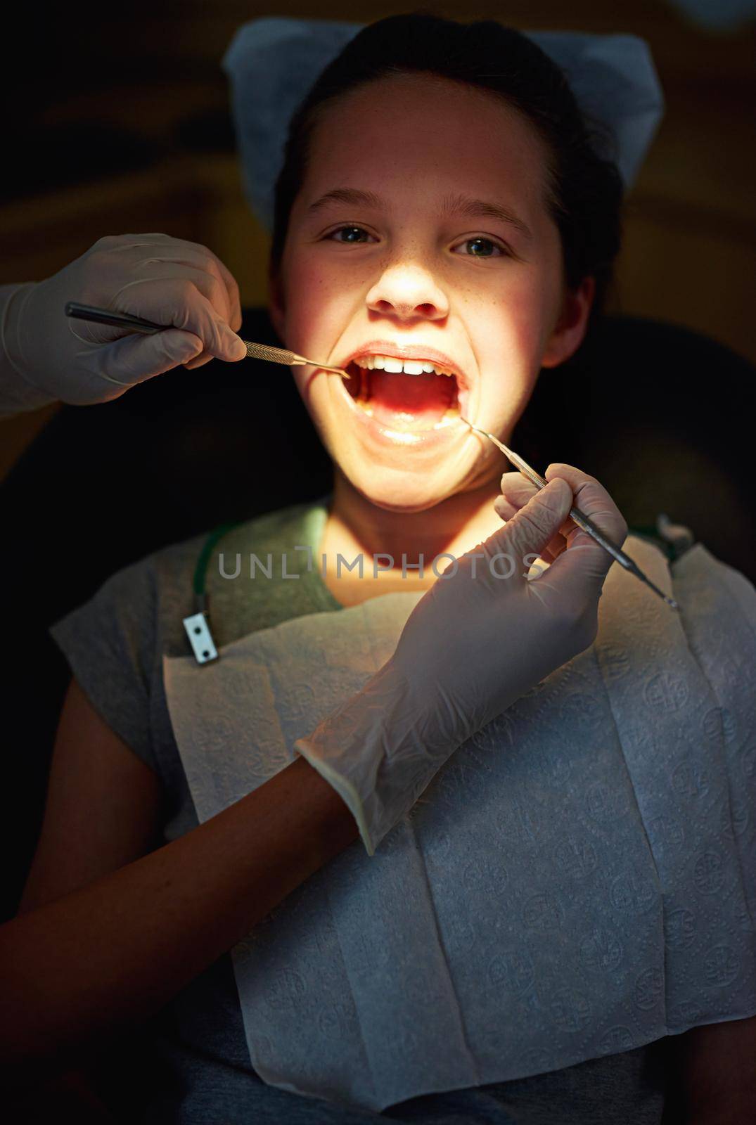 Under the dentists light. Closeup shot of a young girl having a checkup at the dentist. by YuriArcurs