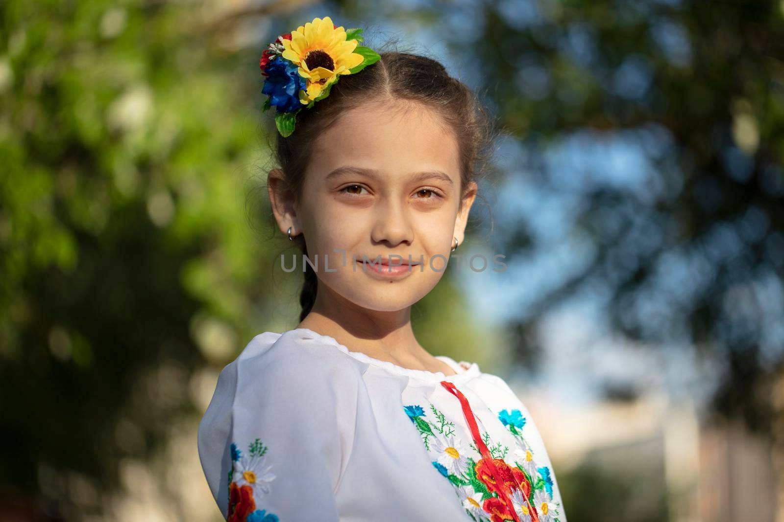 A little Ukrainian and Belarusian girl in an embroidered shirt on a summer background.