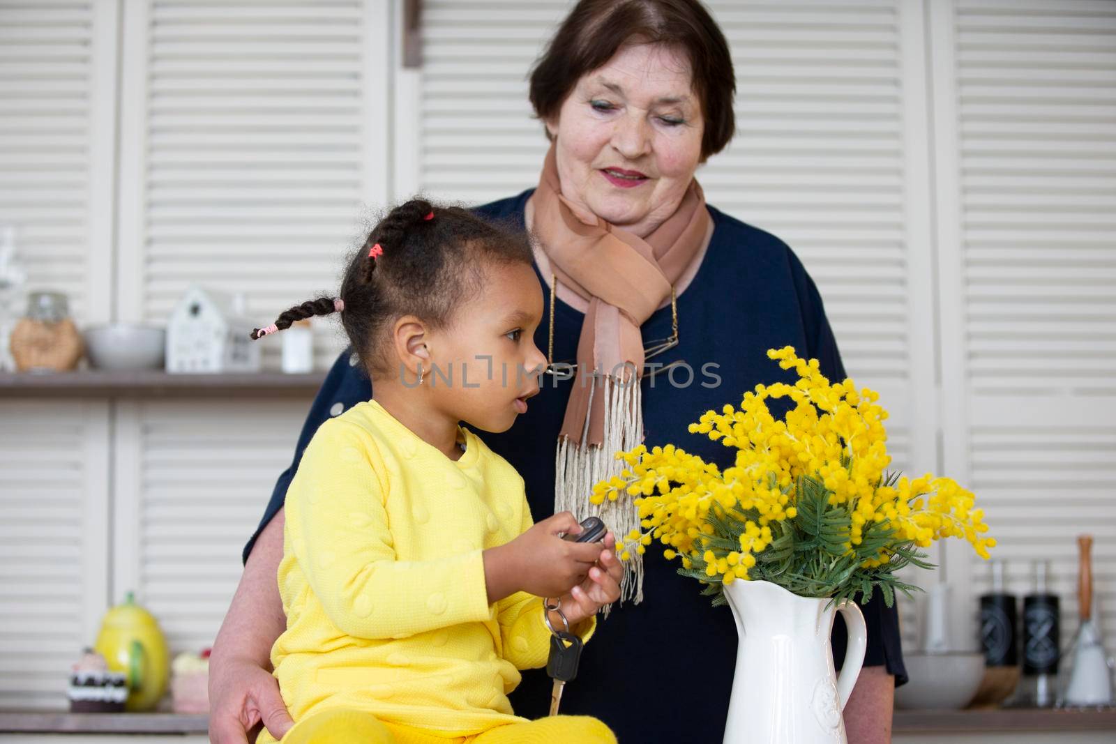Grandmother and granddaughter from different races. The fair-skinned grandmother plays with the dark-skinned granddaughter.