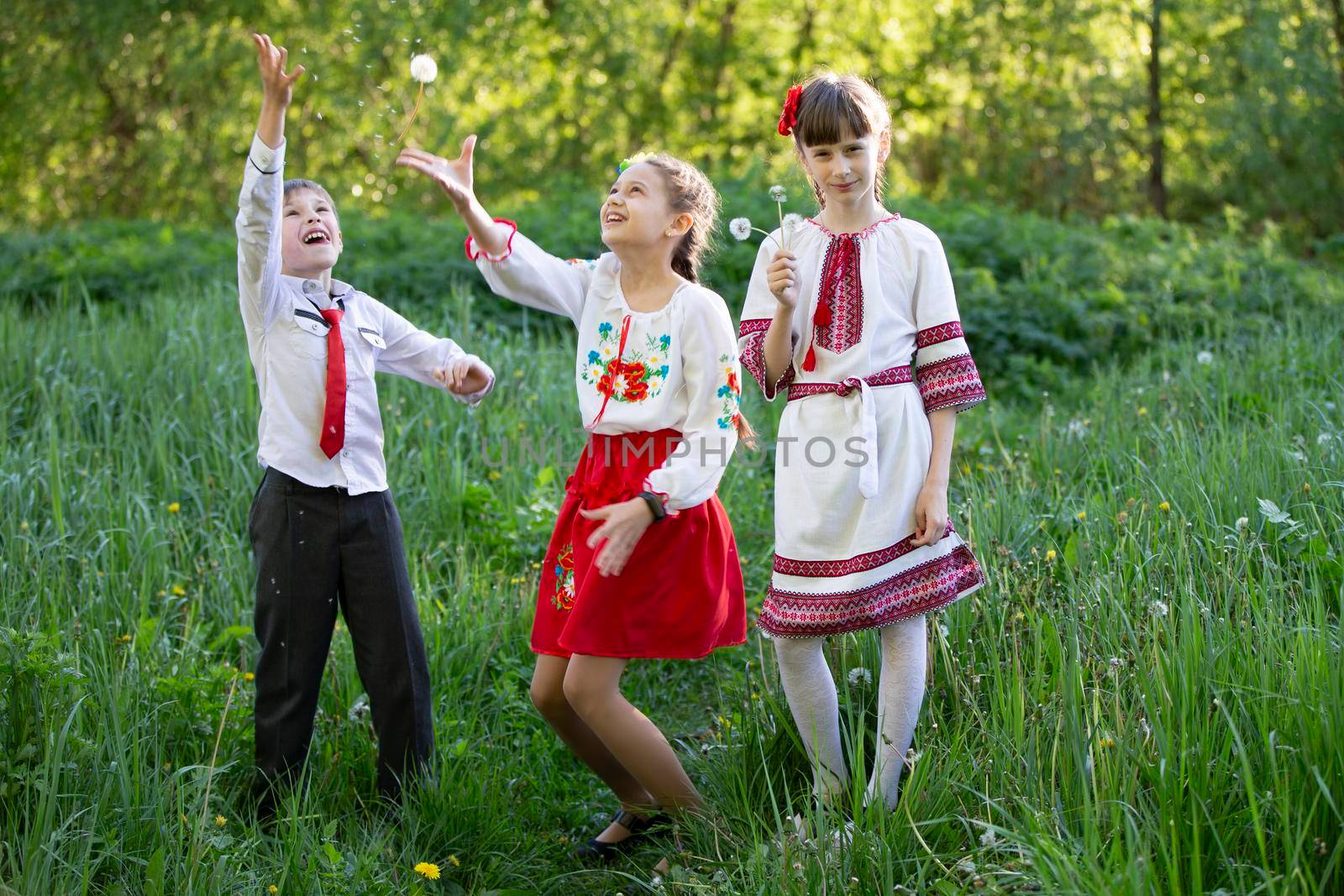 Ukrainian or Belarusian children in embroidered shirts play in the meadow.